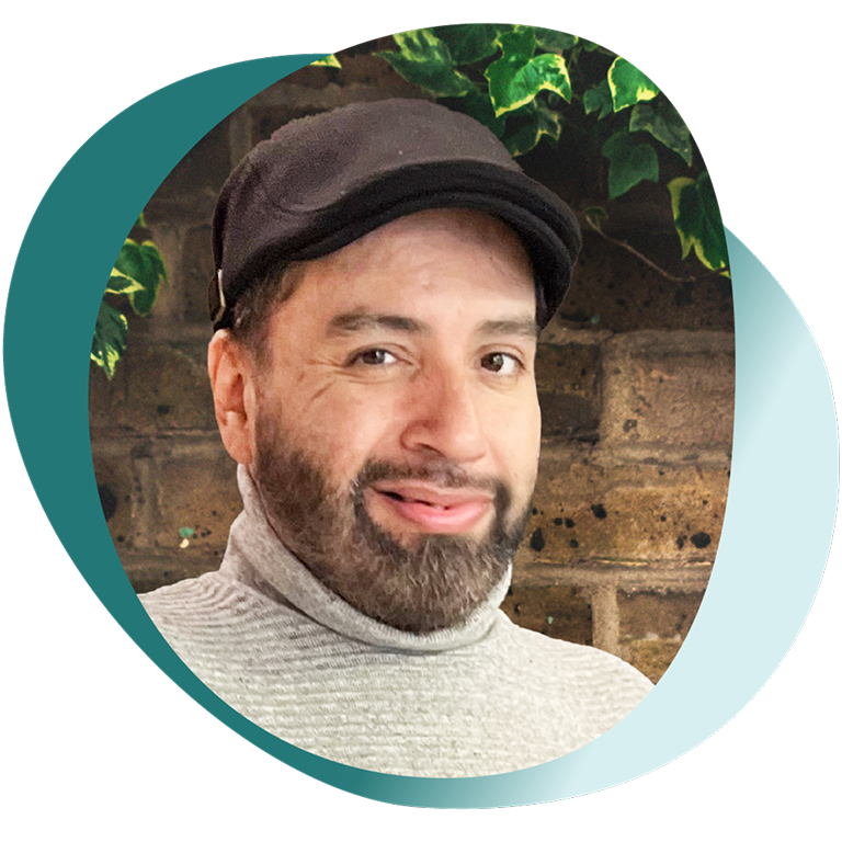 Portrait of Jimmy, a person living with GPP, smiling with a green and brick background